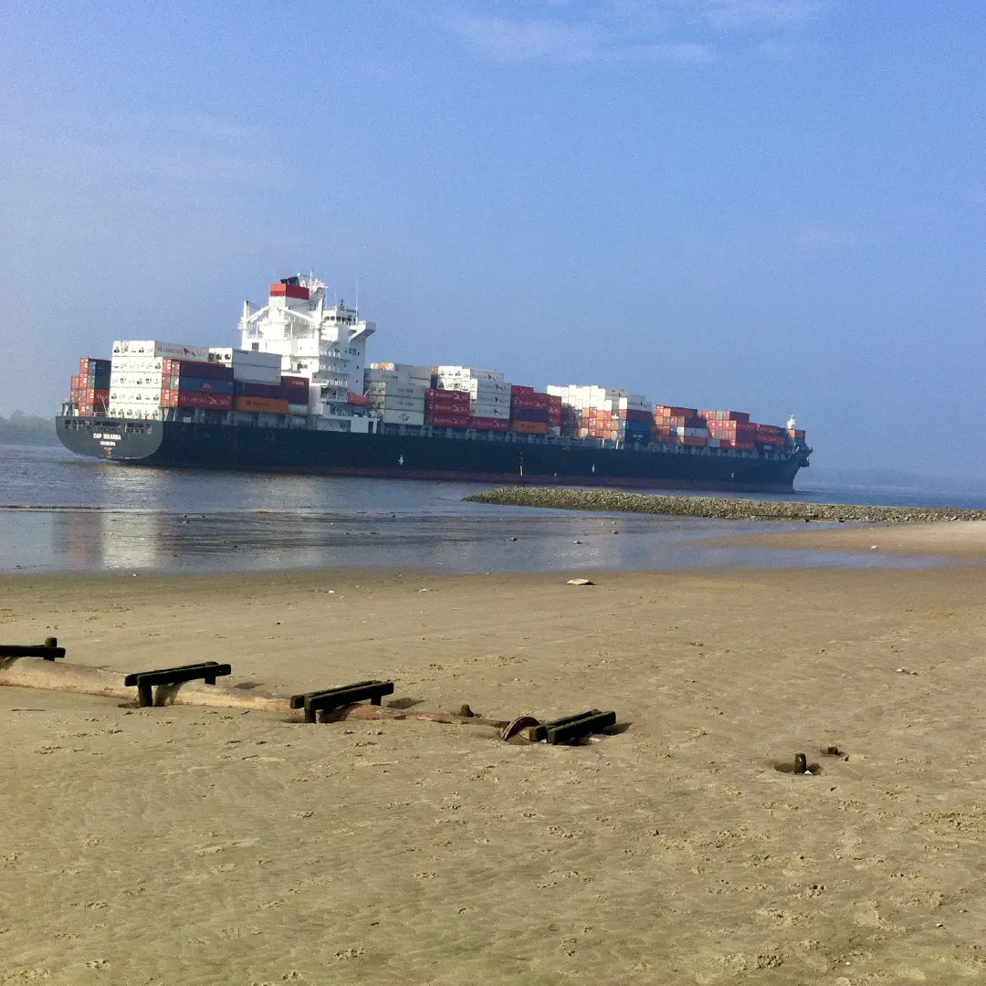 Empty beach in Hamburg Wittenbergen. Two large container ships pass on the Elbe.