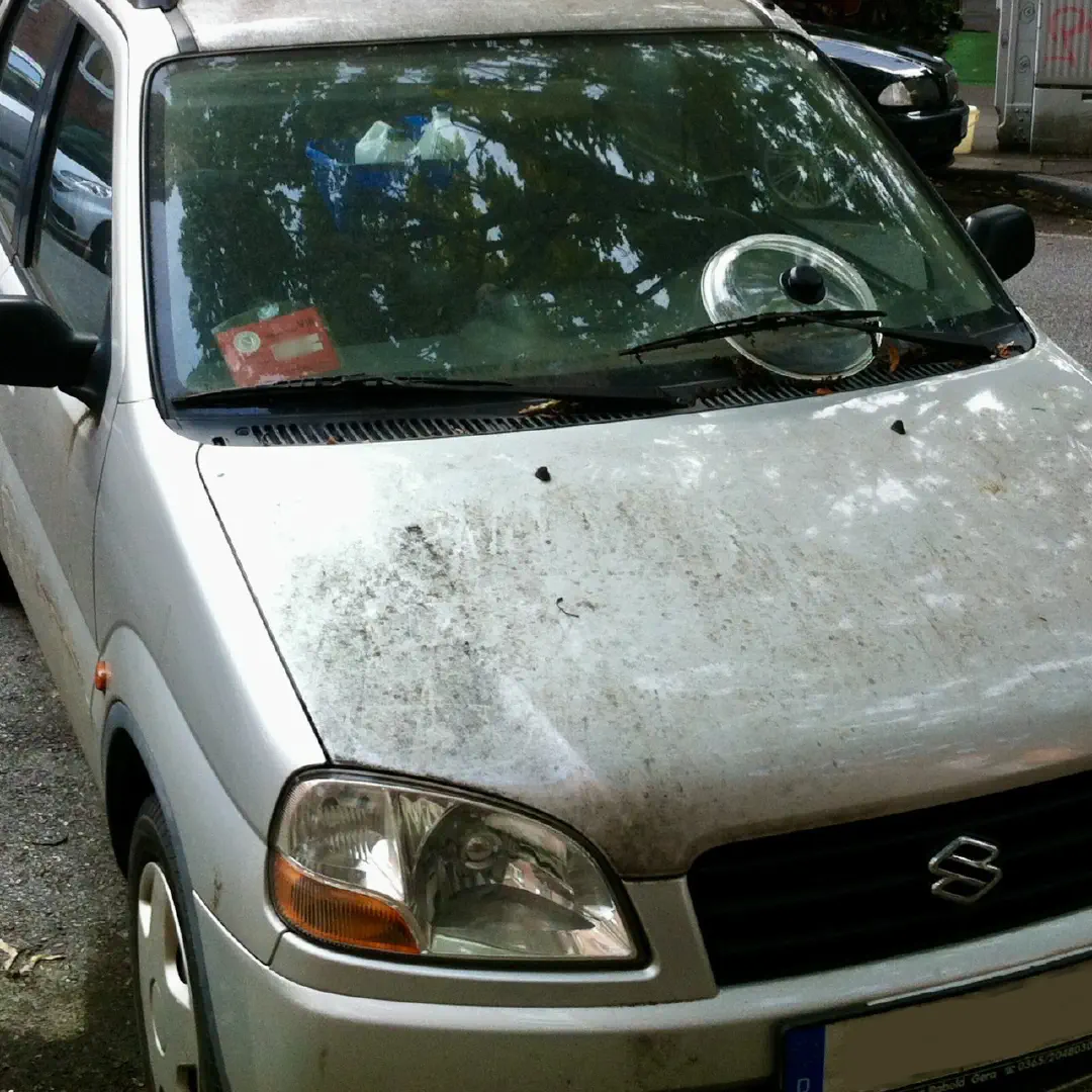 A dirty hatchback car with the lid of a saucepan on the front window